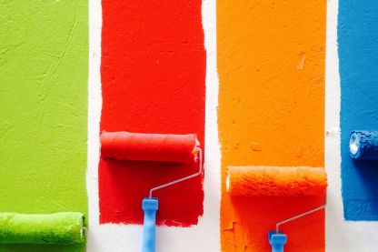 Vier farbige Anstriche in Grün, Rot, Orange und Blau nebeneinander an einer weißen Wand