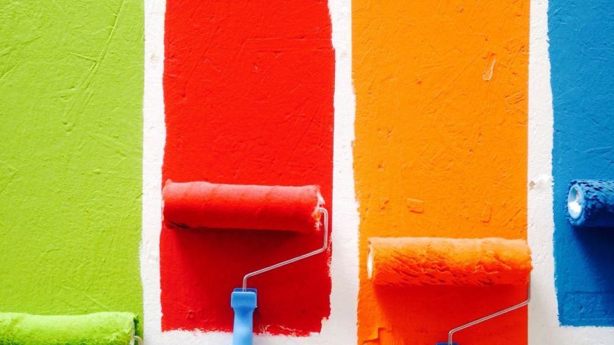 Vier farbige Anstriche in Grün, Rot, Orange und Blau nebeneinander an einer weißen Wand